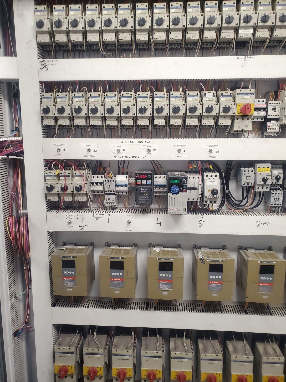 Custom motor control panel built in-house by McClone Electric for a grain elevator, showing labeled motor starters and color-coded wiring