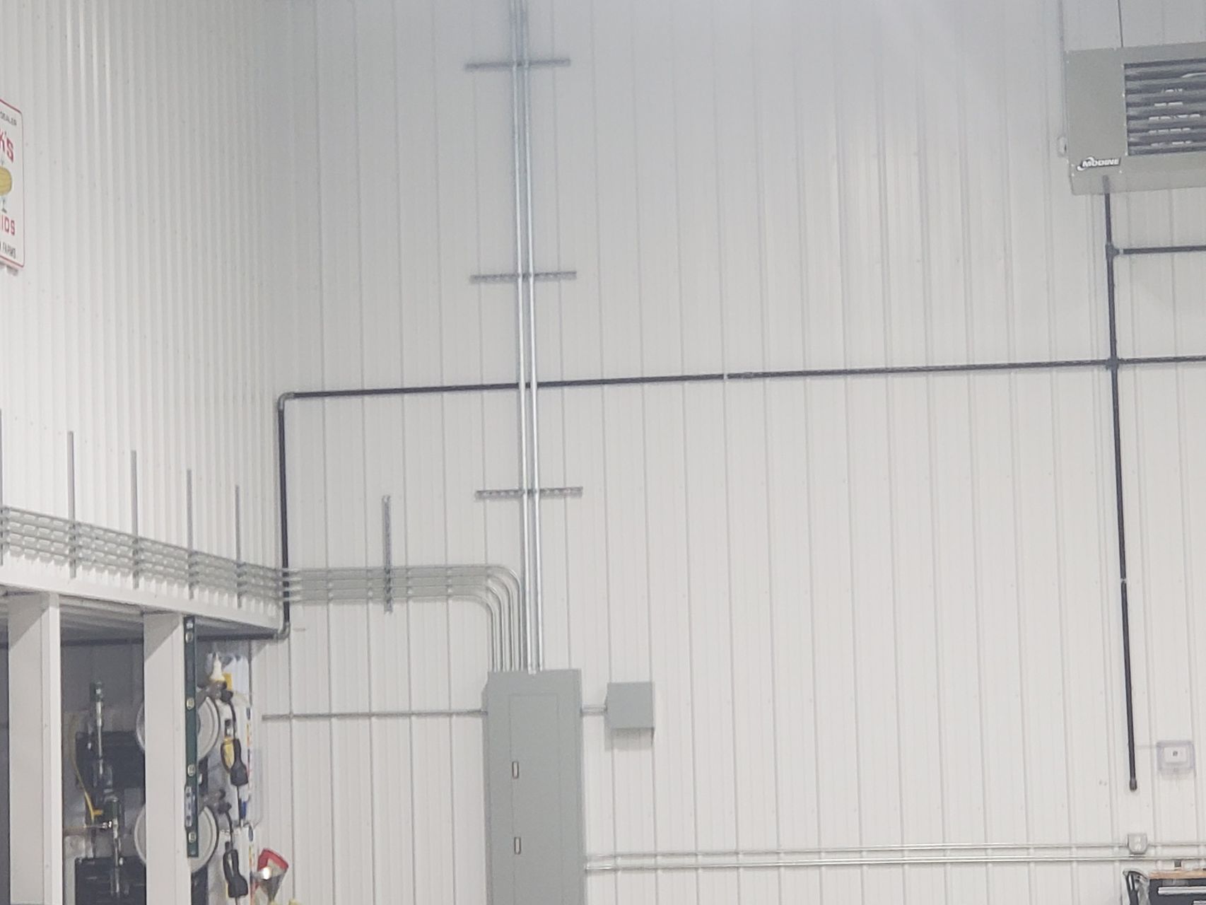 Surface conduit runs and an electrical panel feeding lighting and a unit heater in a shop building, installed by McClone Electric